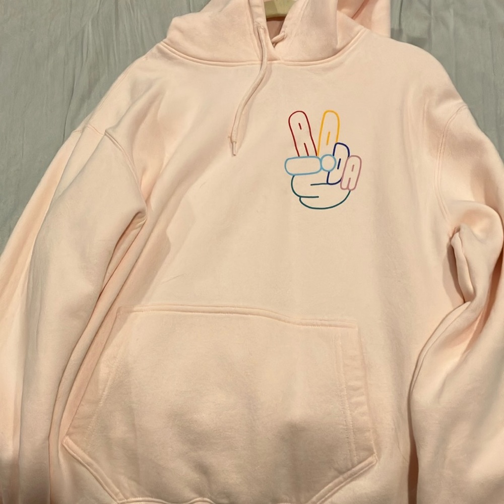 Adidas pink hoodie with brand name in rainbow colors making peace sign.